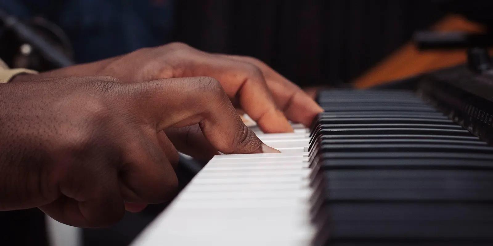 Close-up of a musician's hands playing a piano keyboard.