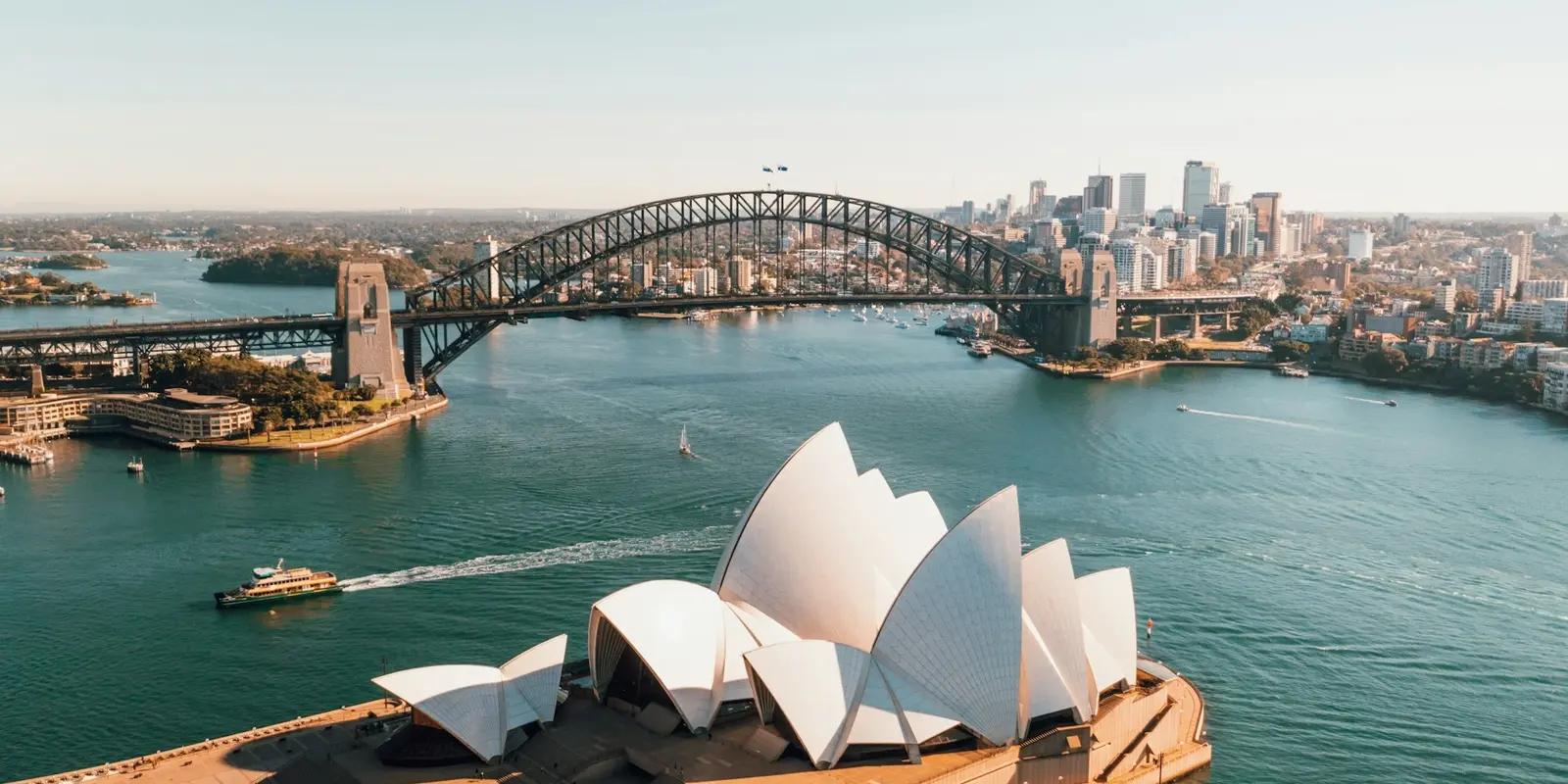 Aerial view of the Sydney Opera House and Sydney Harbour Bridge with the city skyline in the background.