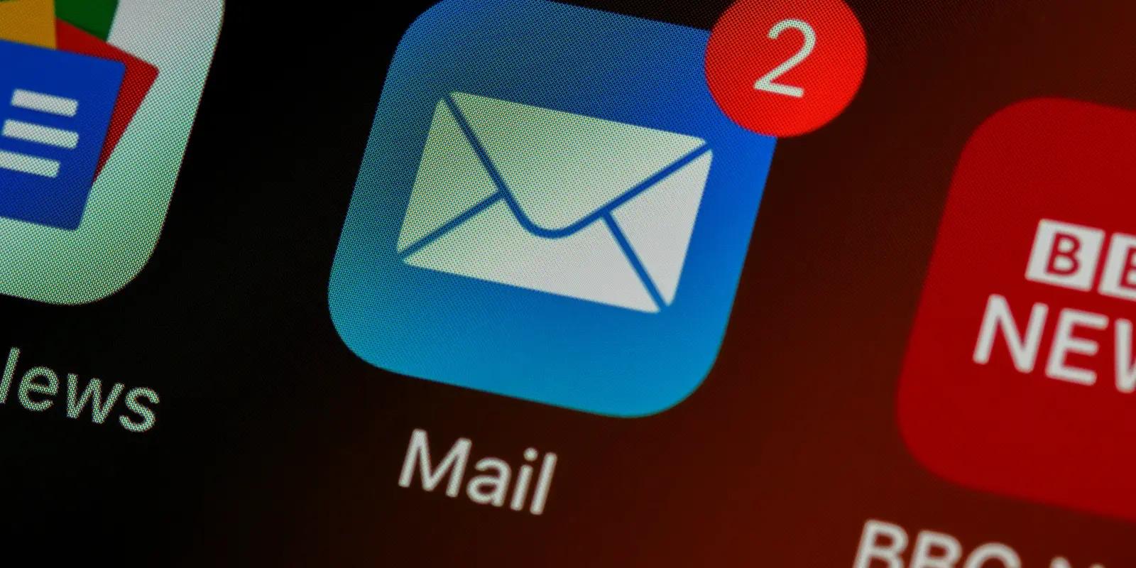 A close-up of a smartphone screen showing the Mail app icon with a red notification badge displaying '2' unread messages, alongside other app icons like BBC News and Google News.
