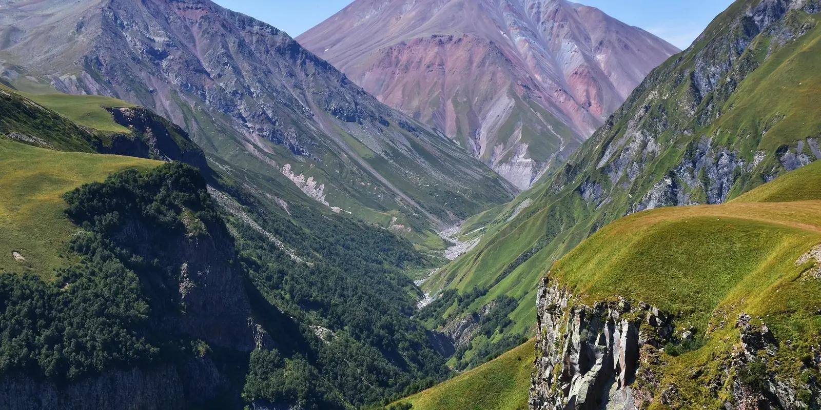 Dramatic green valleys and red-hued mountain peaks in Georgia's Caucasus range.