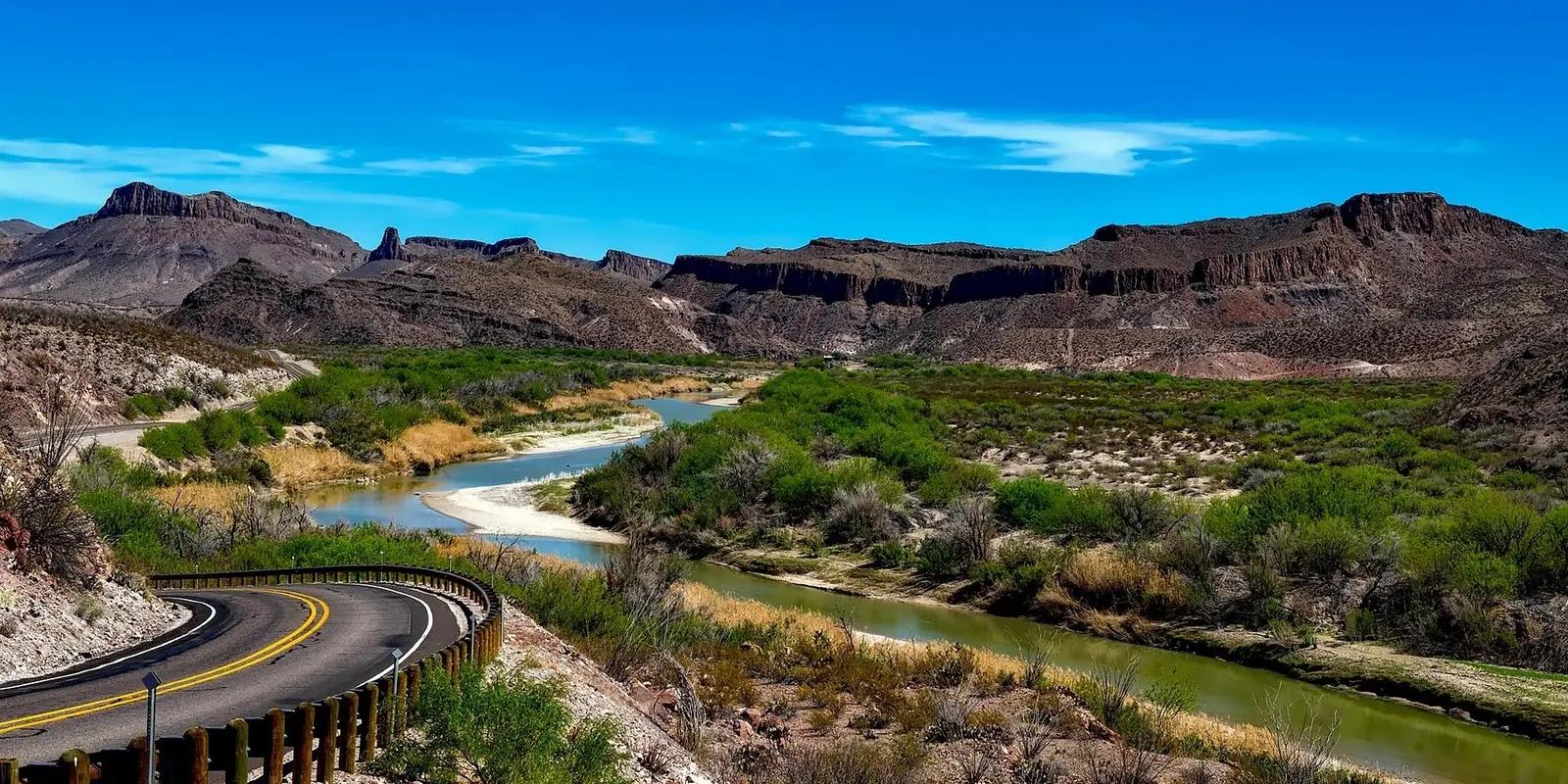 Winding Rio Grande River flowing through Big Bend National Park, Texas, with rugged mountains, desert vegetation, and a curved road overlooking the dramatic river valley landscape.