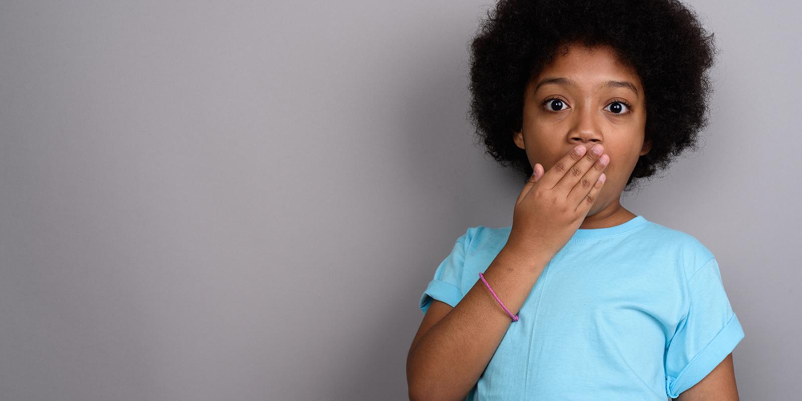 A young person with a surprised expression and hand over their mouth, possibly experiencing hiccups.