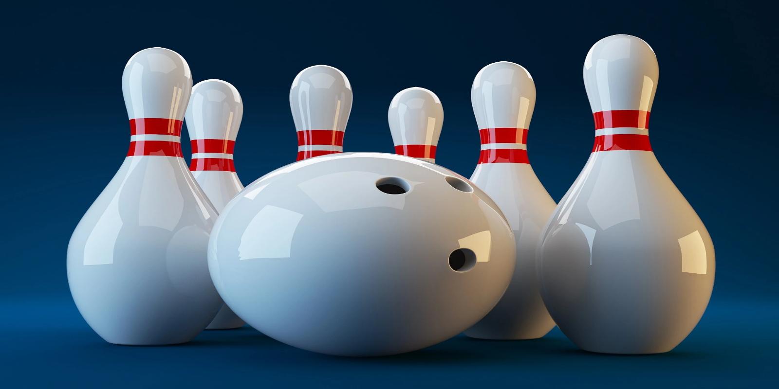 Close-up of a white bowling ball in front of six white bowling pins with red stripes on a blue background.