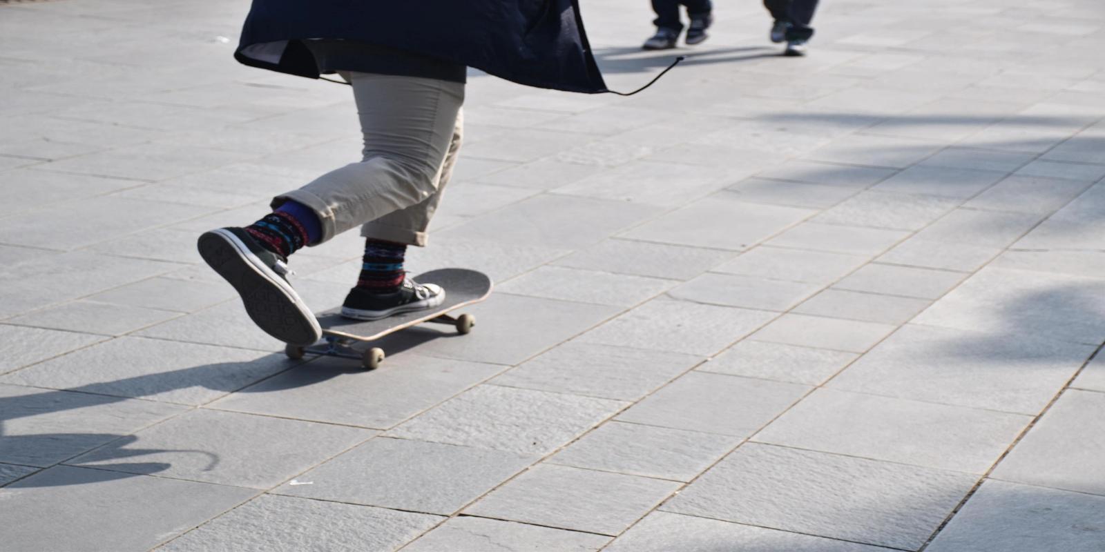 Person skateboarding on a paved surface, wearing casual clothes and colorful socks.